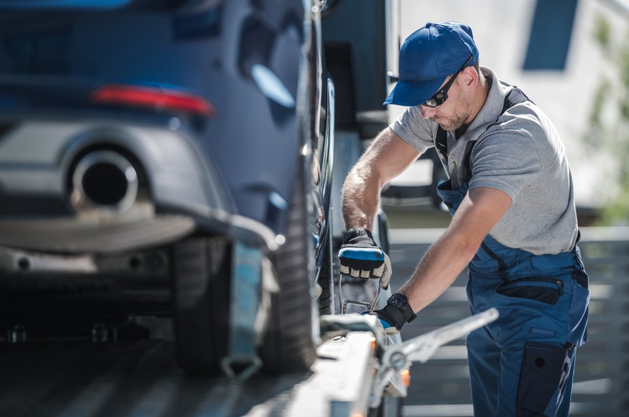A tow truck operator loading a car