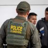 Border Patrol police officer in a green vest speaks with suspects during a traffic stop.