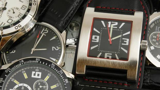 Stack of counterfeit wristwatches seized by CBP on a table.