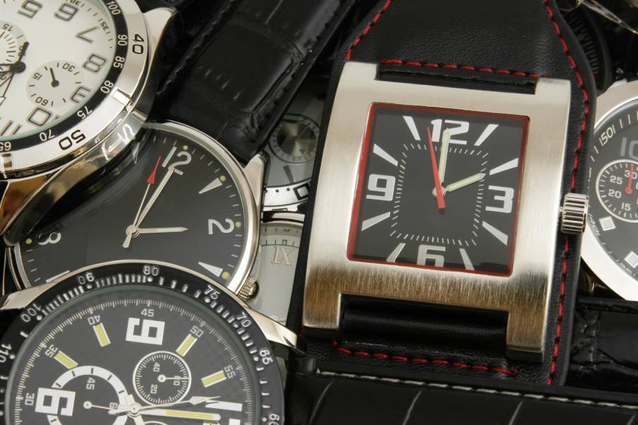 Stack of counterfeit wristwatches seized by CBP on a table.