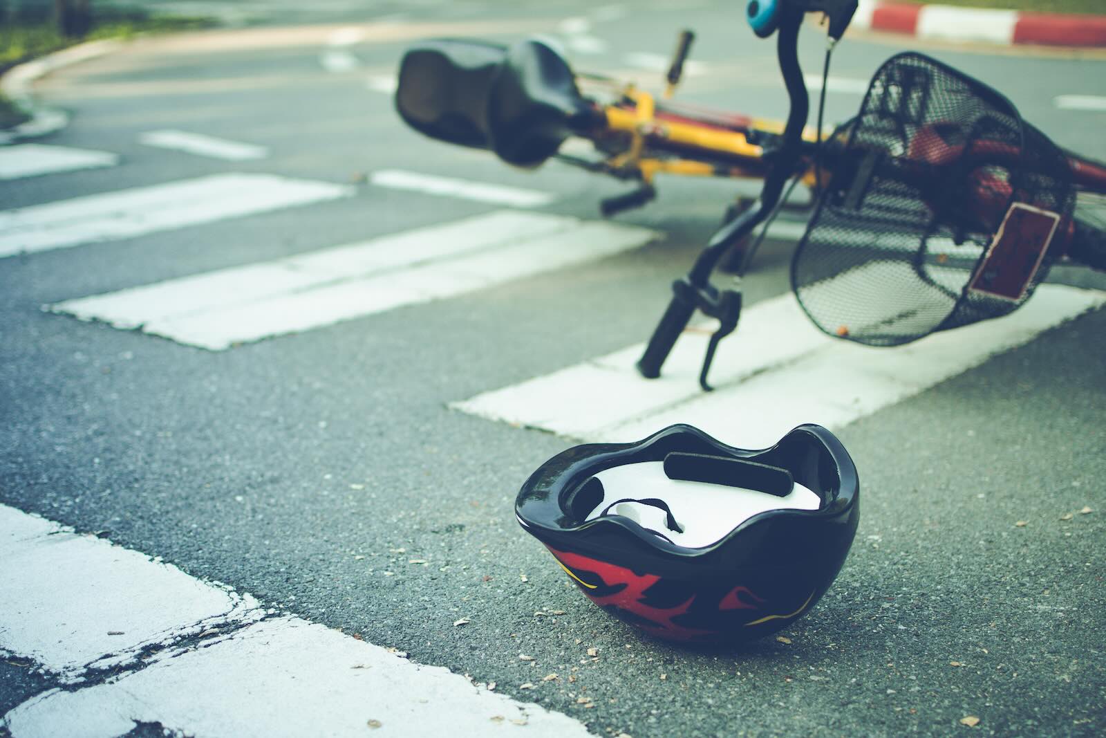 eBike left in crosswalk after a crash, helmet in the foreground.