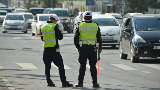 two police officers standing on the side of a road.