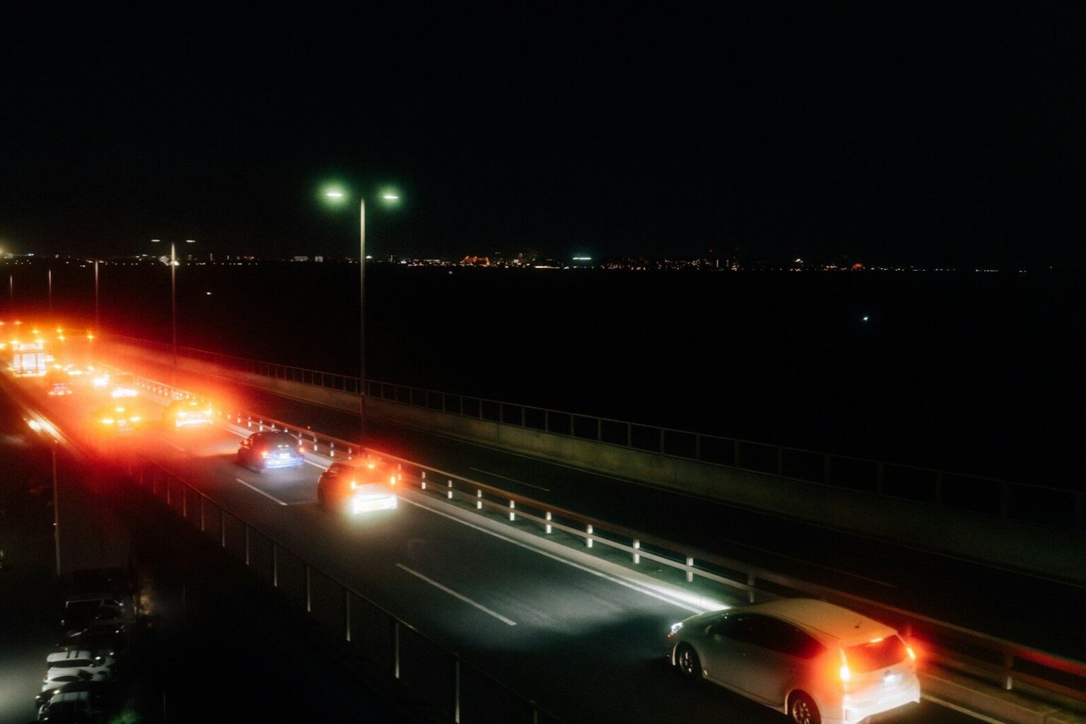 Cars driving on a highway at night with city lights.