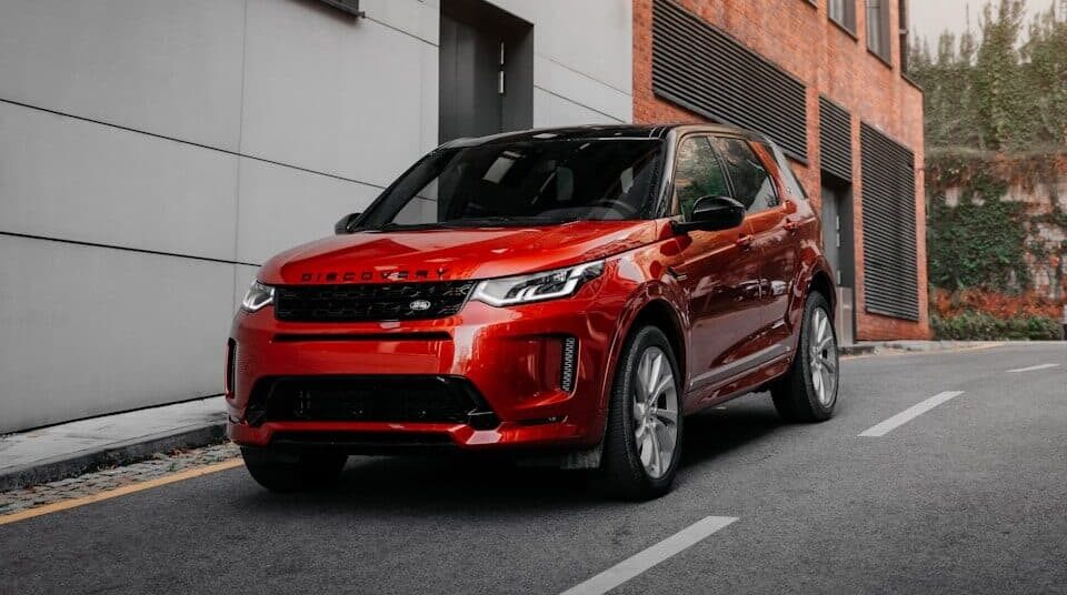 red car parked beside white concrete building during daytime