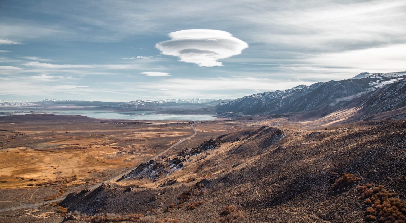 a large cloud hovering over a mountain range. UFO