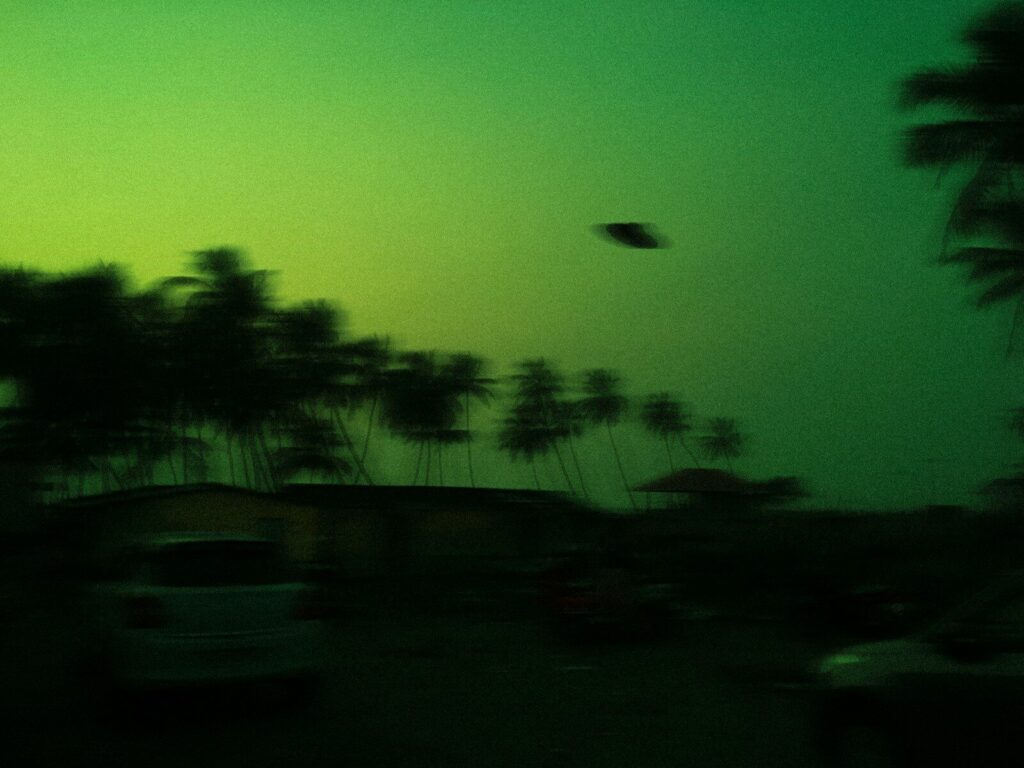 green and black trees under blue sky. UFO