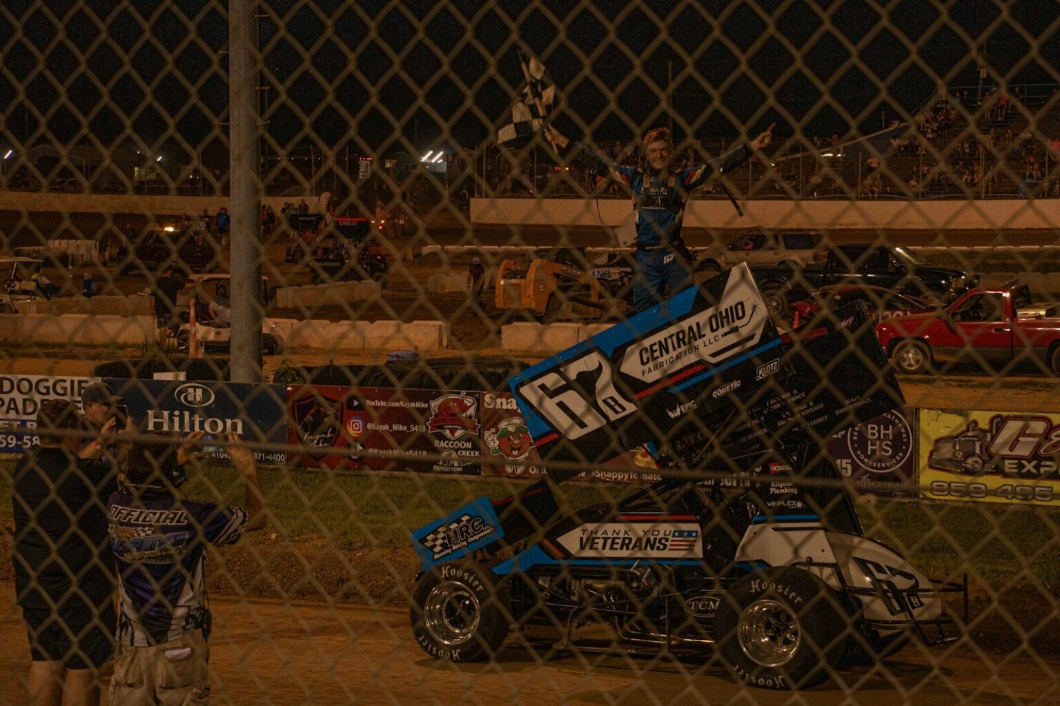 Sprint car driver celebrates victory with checkered flag
