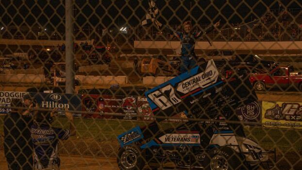 Sprint car driver celebrates victory with checkered flag