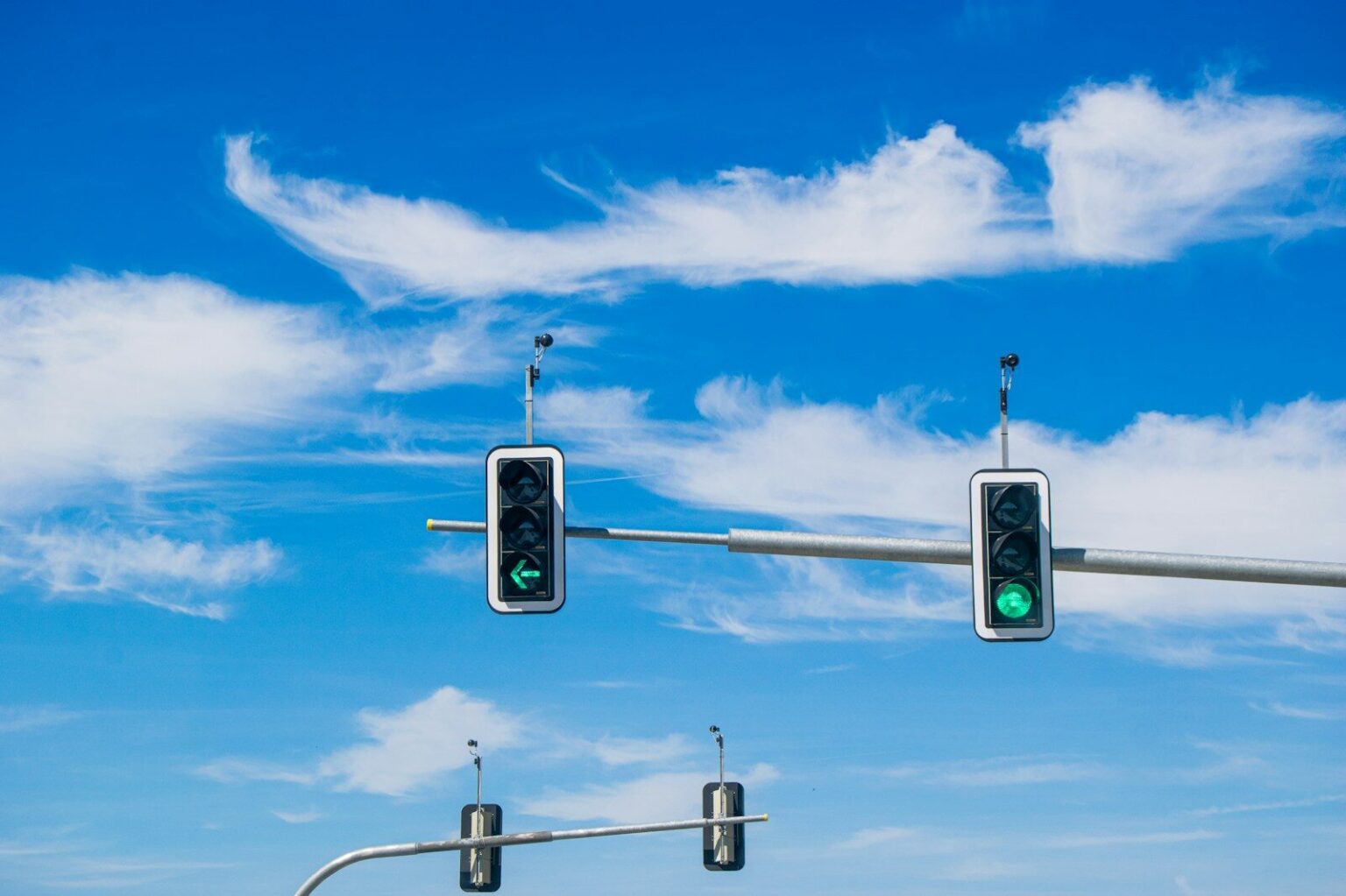 Traffic lights are green against a blue sky.
