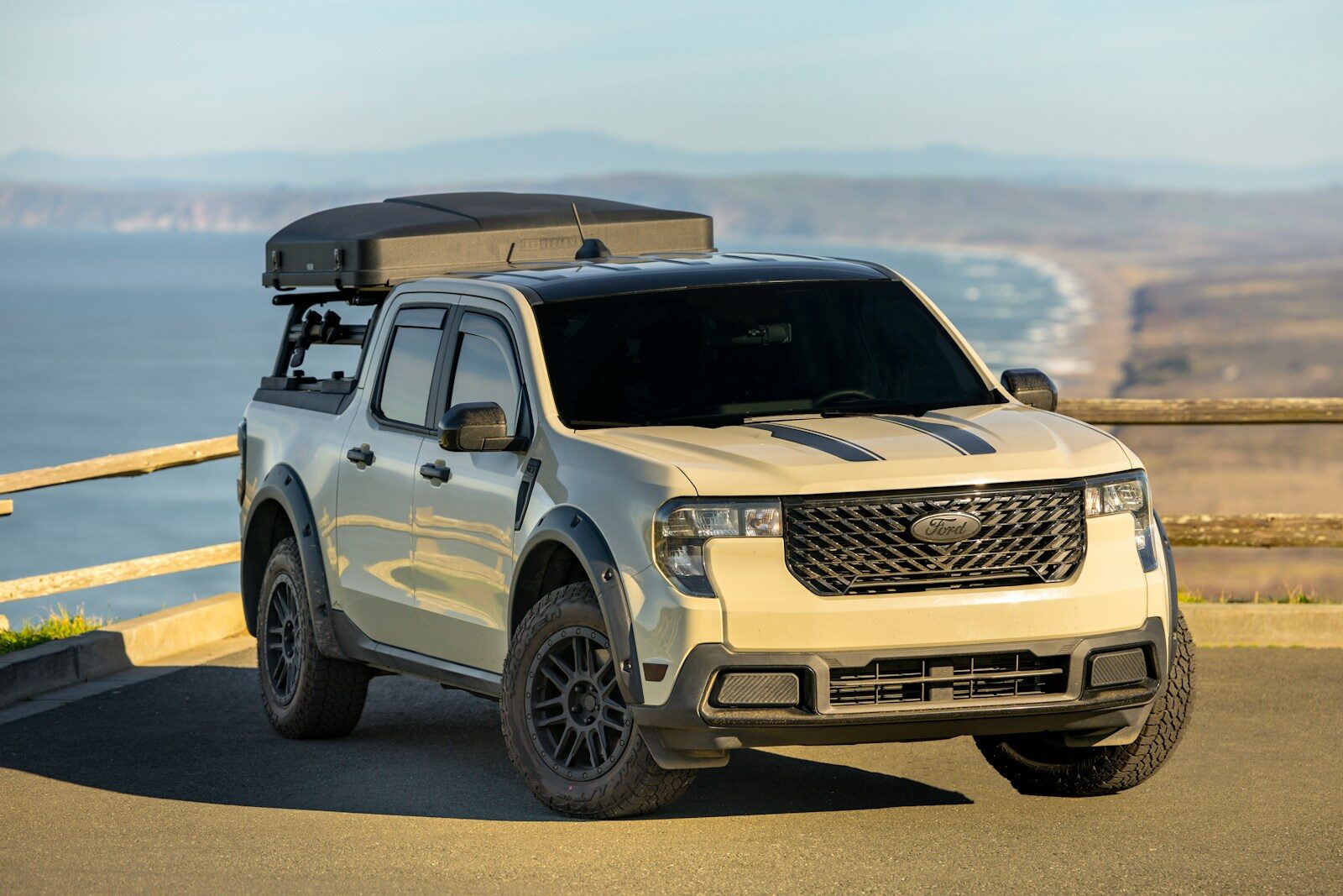 Tan pickup truck with rooftop tent overlooks ocean