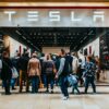 a group of people standing outside of a building- Tesla