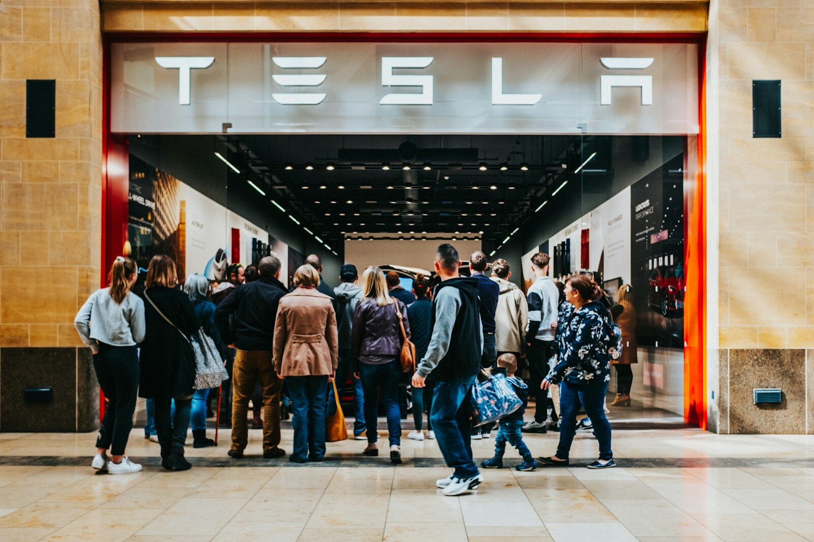 a group of people standing outside of a building- Tesla
