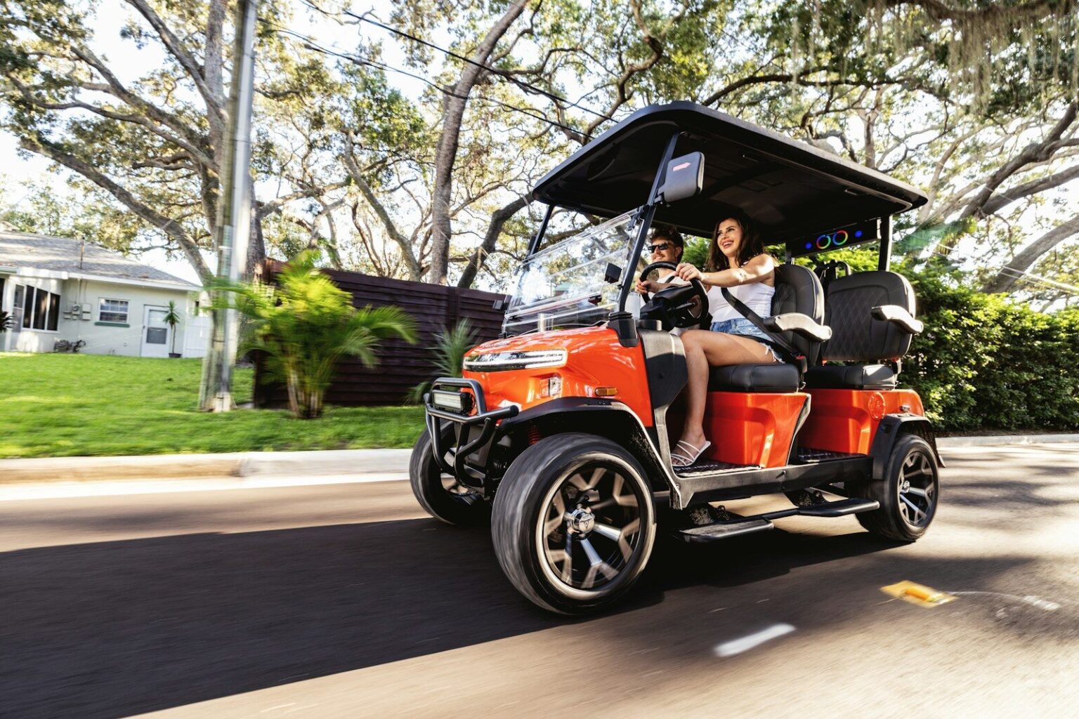 Two people riding in a golf cart on a street