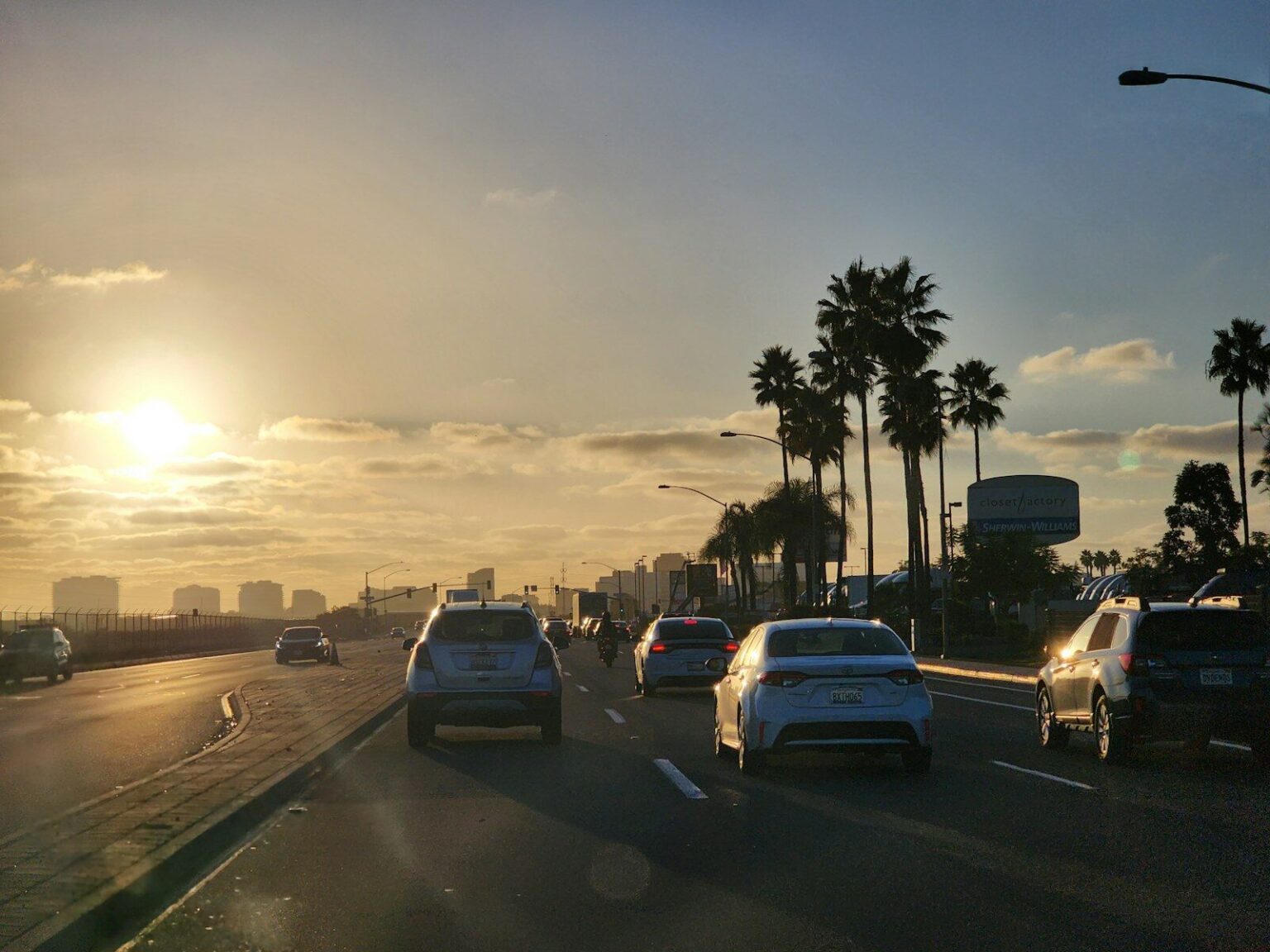 A group of cars driving down a street next to palm trees