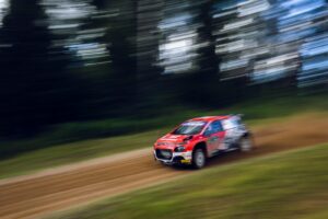 A red car driving down a dirt road
