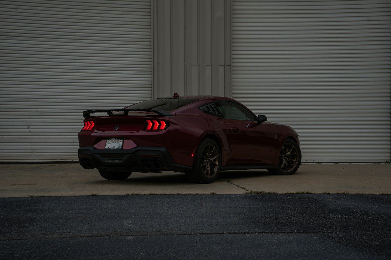 Maroon car parked in front of a gray building.