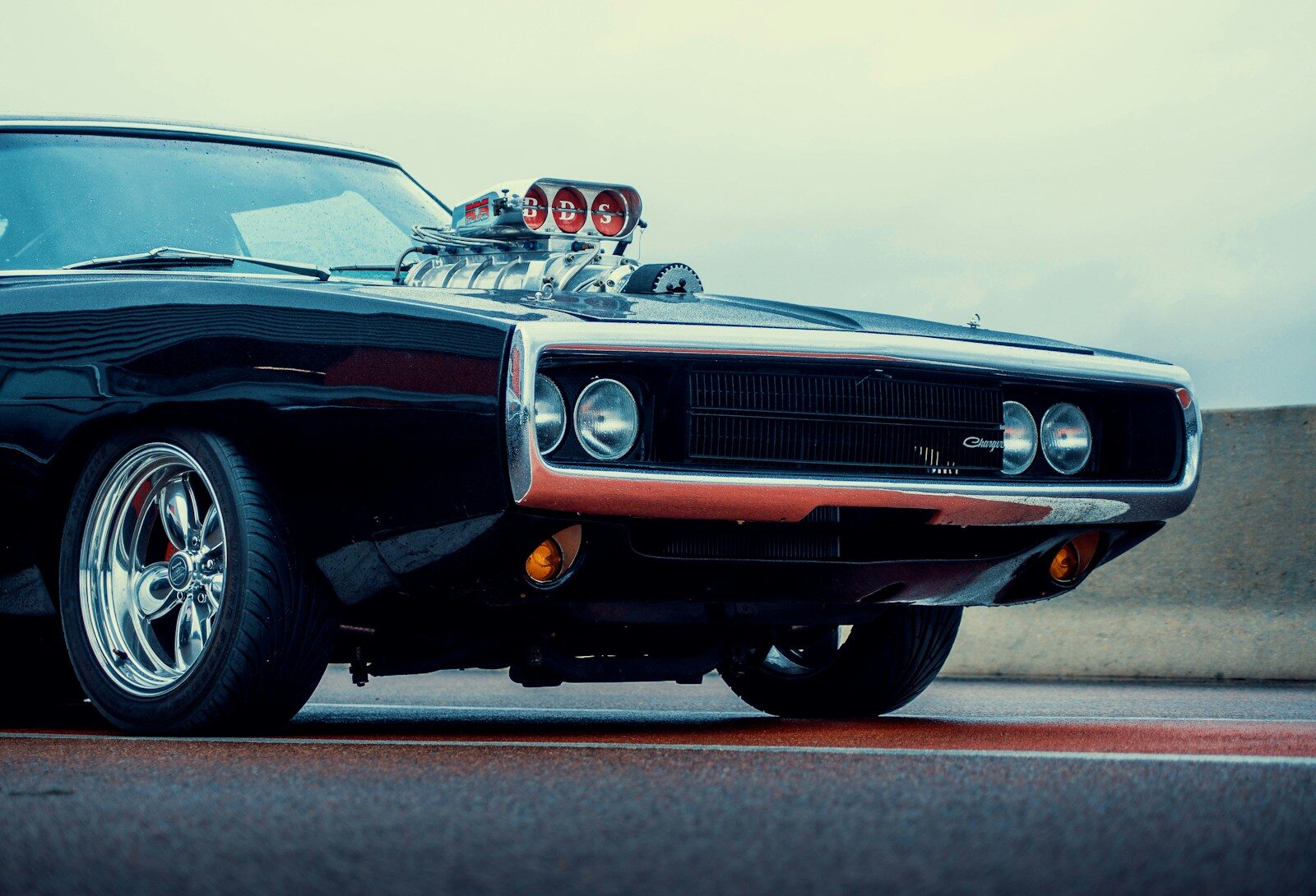 a black muscle car with chrome rims parked on the street