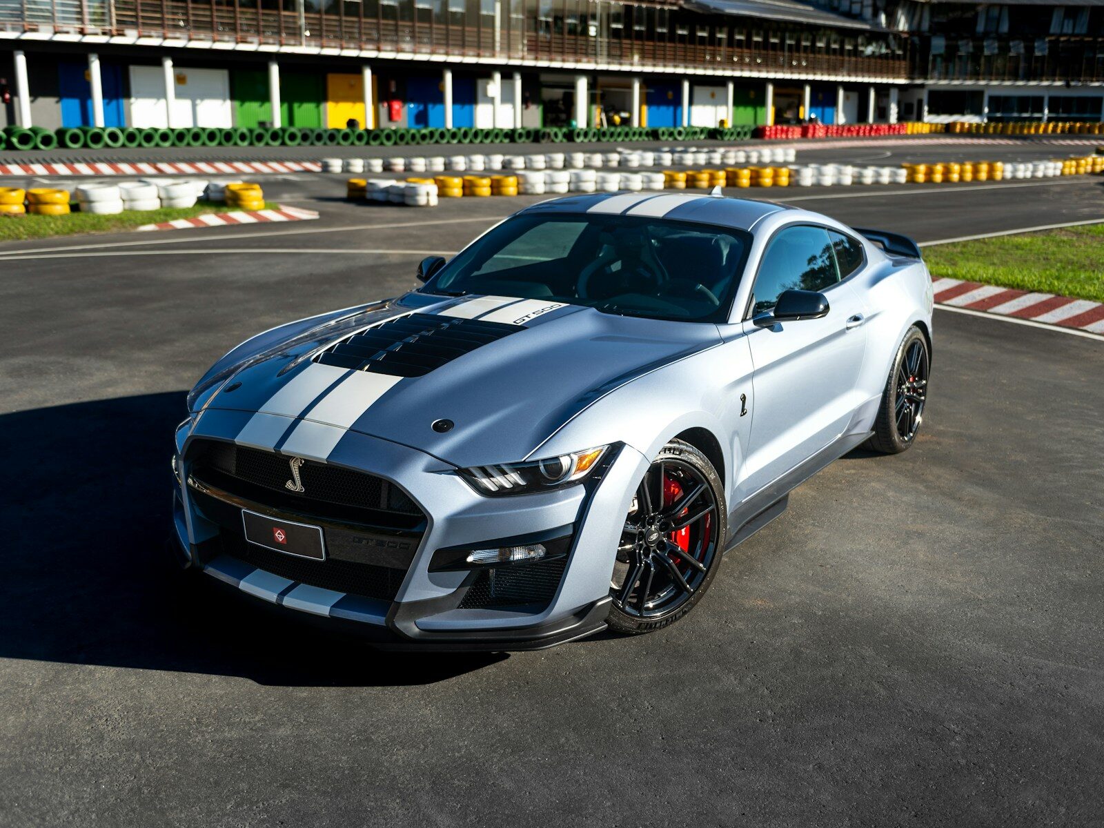 A silver shelby mustang is shown on a racetrack.