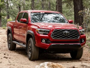 A red toyota tacoma truck parked on a dirt road