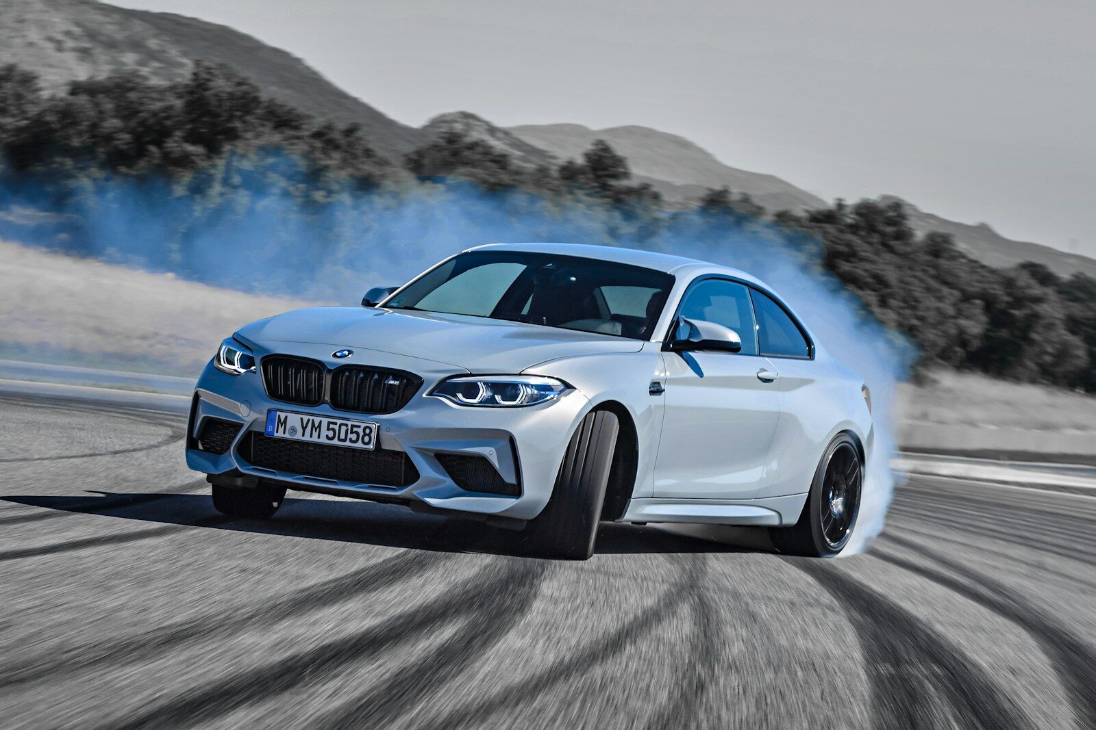 a white bmw car driving down a road