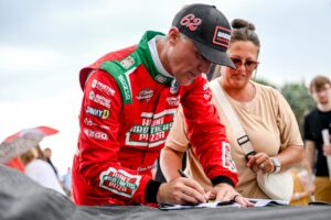 Former NASCAR Cup Series champion Kevin Harvick signs items for fans during an autograph session before the 13th annual Masters