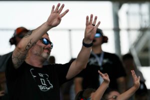 A fan wearing a Kyle Busch shirt cheers from the stands Sunday, July 26, 2026, during the Brickyard 400 at Indianapolis Motor